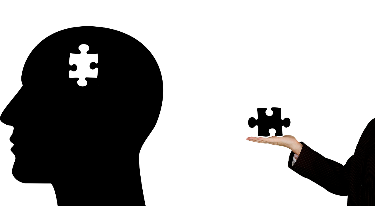 depression treatment - black silhouette with a missing puzzle piece and an arm holding the piece