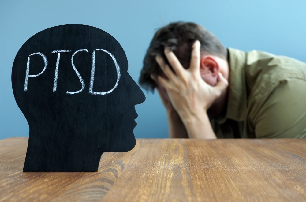 PTSD Treatment - man holding head in hands next to head silhouette that reads PTSD